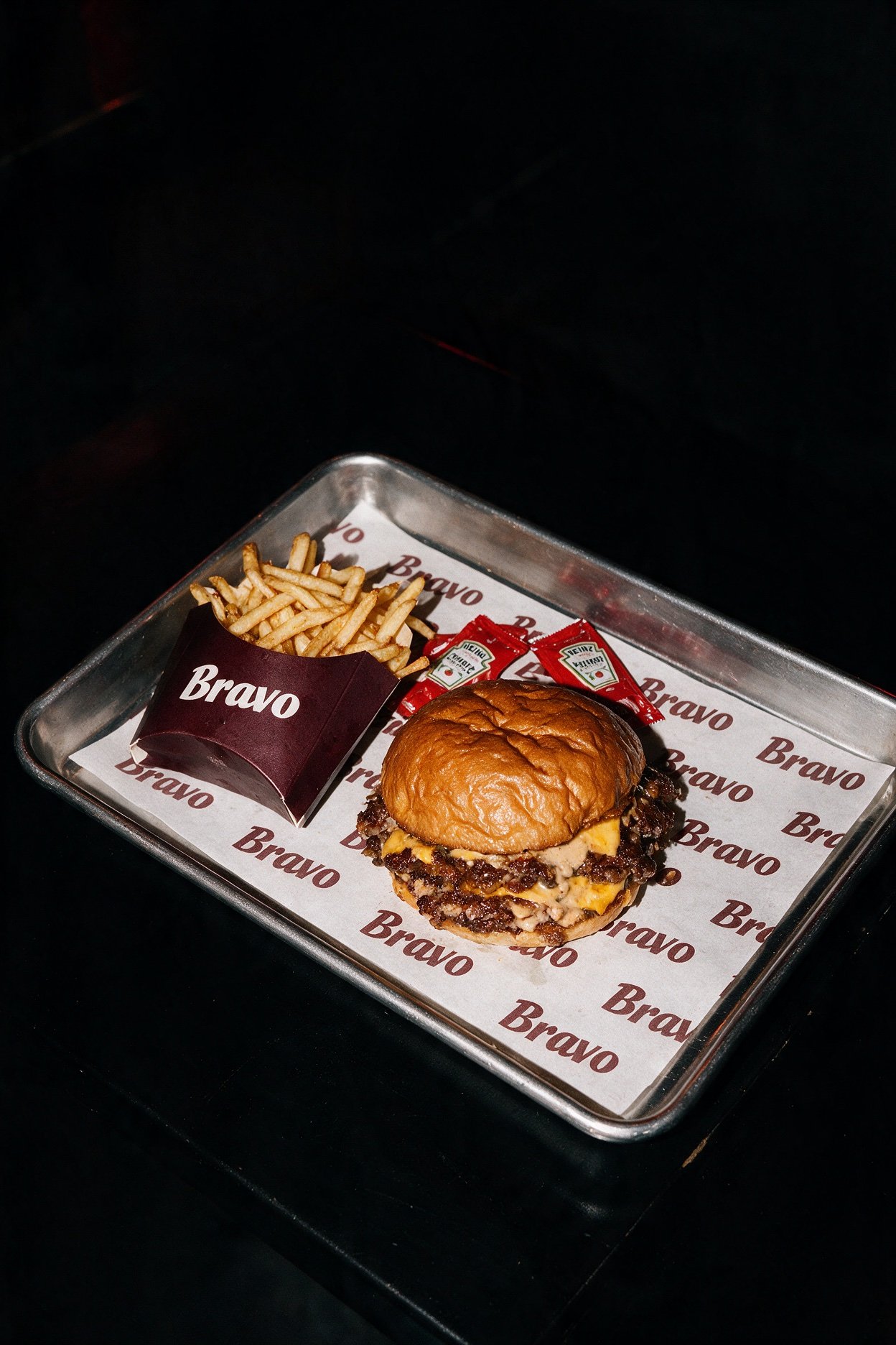 Hamburguesa y patatas en una bandeja con la identidad de Bravo